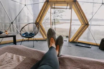 a person laying on a couch with their feet up on a bed at Asalnai Campsite in Ignalina
