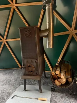 a wood stove in a room with a basket of logs at Asalnai Campsite in Ignalina