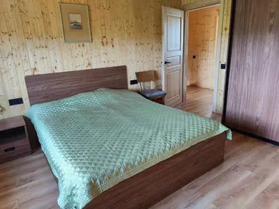a bedroom with a bed and a wooden floor at Modern family house by the lake in Zarasai in Štadviliai