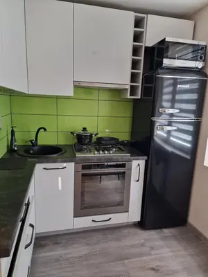 a kitchen with white cabinets and a black refrigerator at Butas in Kaunas