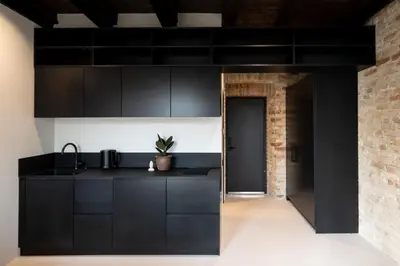 a kitchen with black cabinets and a brick wall at Hortus Vilnius in Vilnius
