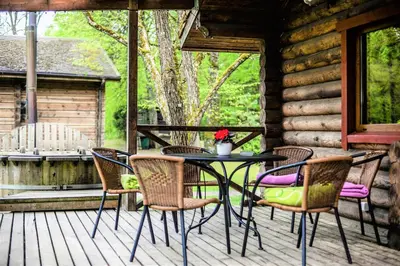 a table and chairs on a porch of a cabin at Sodyba Duburiai in Ukmergė