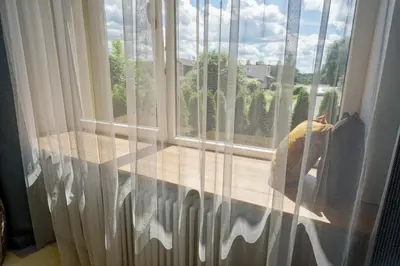 a window with curtains and a person looking out at Munu Holiday Apartments in Druskininkai