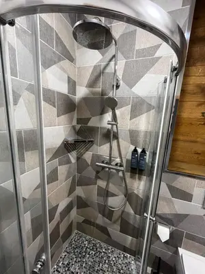 a shower in a bathroom with a tiled wall at Munu Holiday Apartments in Druskininkai
