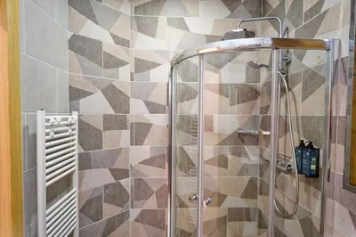 a shower in a bathroom with mosaic tiles at Munu Holiday Apartments in Druskininkai