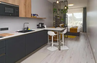 a kitchen with a sink and a counter with stools at Munu Holiday Apartments in Druskininkai