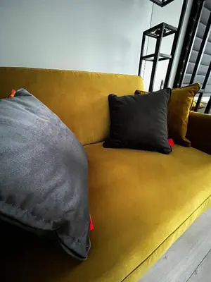 a yellow couch with two pillows on it at Munu Holiday Apartments in Druskininkai