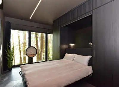 a bedroom with a bed and a large window at Premium Forest Bungalow With Hot Tub & Sauna in Luokesos Sen