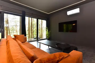 a living room with a large orange couch and a table at Premium Forest Bungalow With Hot Tub & Sauna in Luokesos Sen