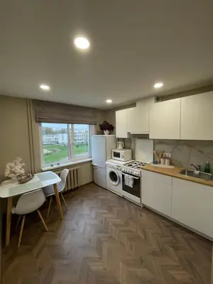a kitchen with white cabinets and a table and a stove at Comfort home Šiauliai in Šiauliai