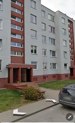 a large building with a car parked in a parking lot at Comfort home Šiauliai in Šiauliai
