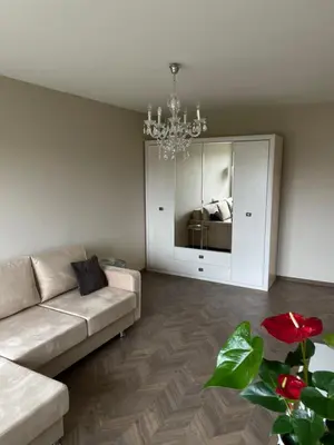 a living room with a couch and a chandelier at Comfort home Šiauliai in Šiauliai