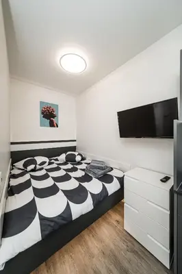 a bedroom with a black and white bed and a flat screen tv at Riverra House in Kaunas