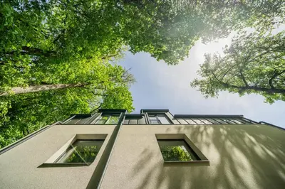 a building with two windows and trees in the sky at Riverra House in Kaunas