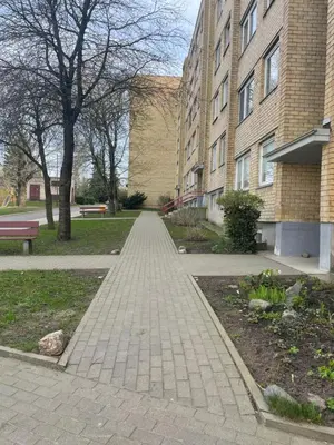 a brick walkway in a park next to a building at Lake Apartment in Šiauliai