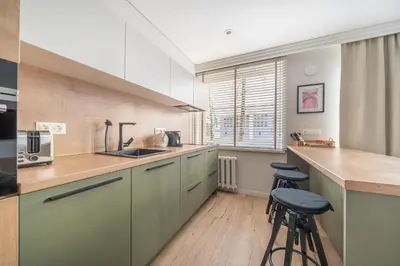 a kitchen with green cabinets and a counter and stools at Lake Apartment in Šiauliai