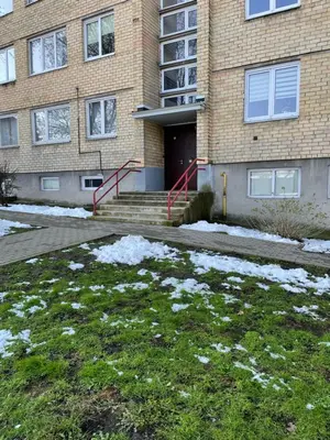 a building with snow on the grass in front of it at Lake Apartment in Šiauliai