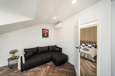 a living room with a black couch and a bed at Riverra House - Panorama View Apartment in Kaunas