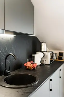 a kitchen counter with a sink and a bowl of fruit at Riverra House - Panorama View Apartment in Kaunas