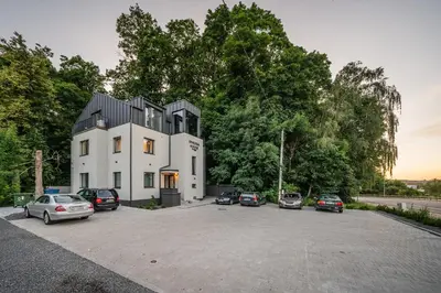 a large white house with cars parked in a parking lot at Riverra House - Panorama View Apartment in Kaunas