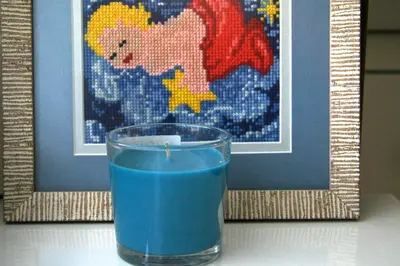 a glass of blue liquid with a candle in front of a picture at Irena Family House in Vilnius