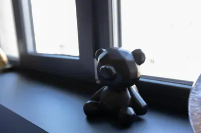 a small black teddy bear sitting on a window sill at Four Sisters Luxury Rooms in Siauliai in Šiauliai