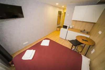 a small room with a red bed and a kitchen at Vilnius Tiny apartments in Vilnius