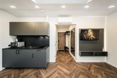 a kitchen with black cabinets and a wooden floor at Riverra House - Two-bedroom Apartment in Kaunas