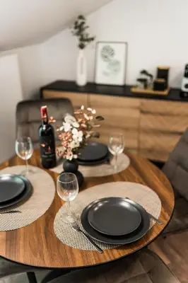 a wooden table with black plates and wine glasses at Riverra House - Two-bedroom Apartment in Kaunas