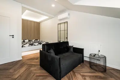 a living room with a black couch and a bed at Riverra House - Studio Panorama View in Kaunas