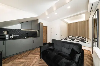 a living room with a black couch and a kitchen at Riverra House - Studio Panorama View in Kaunas