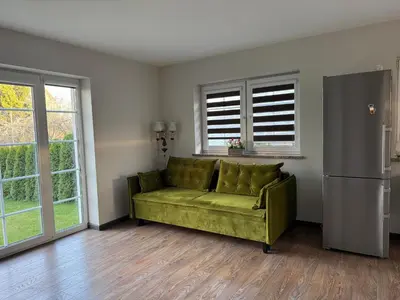 a green couch in a living room with windows at Trakų Namelis in Trakai