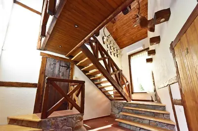 a winding staircase in a house with wooden ceilings at Medžiotojų Sostinė in Kunioniai