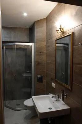 a bathroom with a sink and a shower and a mirror at Medžiotojų Sostinė in Kunioniai