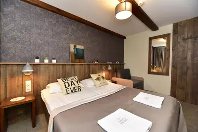 a bedroom with a large bed with two pillows on it at Medžiotojų Sostinė in Kunioniai