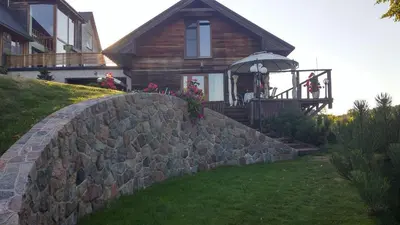 a house with a stone wall in front of a house at Prie Galvės in Trakai