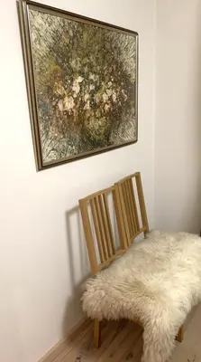 a painting hanging on a wall next to a chair with a rug at Beautiful Vilnius with a terrace in Vilnius