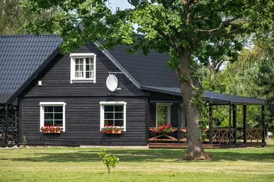 a black house with flowers in front of it at Vila Loreta - visas privatus namas in Dūdorynė