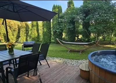 a patio with a hot tub and a hammock at 4 Wheels Cabin in Būda