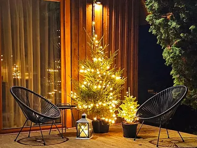 a christmas tree on a porch with two chairs at 4 Wheels Cabin in Būda