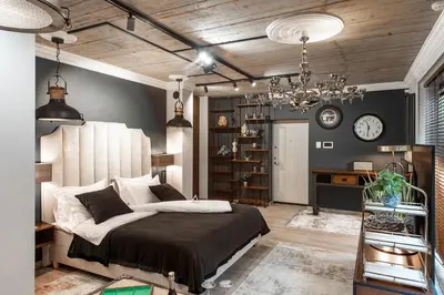 a bedroom with a large bed and a chandelier at Barber Apartment in Kaunas