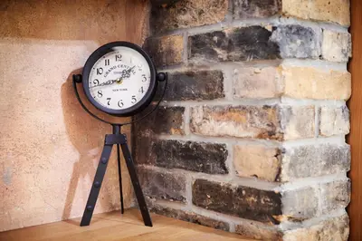 a clock on a tripod next to a brick wall at Old Town Apartments FREE Parking in Vilnius