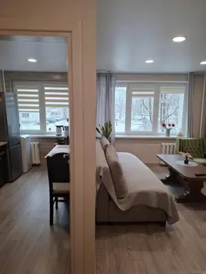 a bedroom with a bed and a table and windows at Apartamentai Auris in Druskininkai