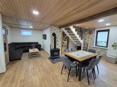 a living room with a table and a fireplace at Namas Zarasuose su vyno rūsiu in Zarasai