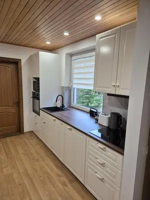 a kitchen with white cabinets and a window at Namas Zarasuose su vyno rūsiu in Zarasai