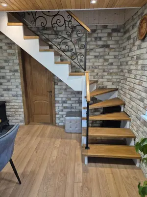 a staircase in a living room with a brick wall at Namas Zarasuose su vyno rūsiu in Zarasai