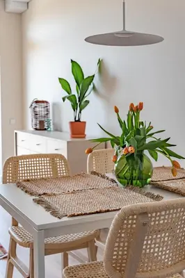 a dining room table with chairs and a vase with flowers at Cozy apartment with huge terrace in Vilnius