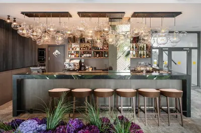 a bar with stools and chandeliers at Harmony Birštonas in Birštonas