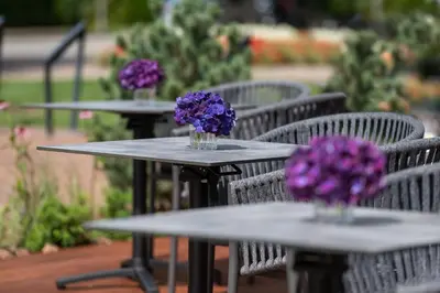 three tables with purple flowers in vases on them at Harmony Birštonas in Birštonas