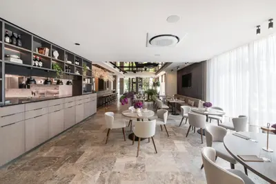 a restaurant with white tables and chairs and a counter at Harmony Birštonas in Birštonas